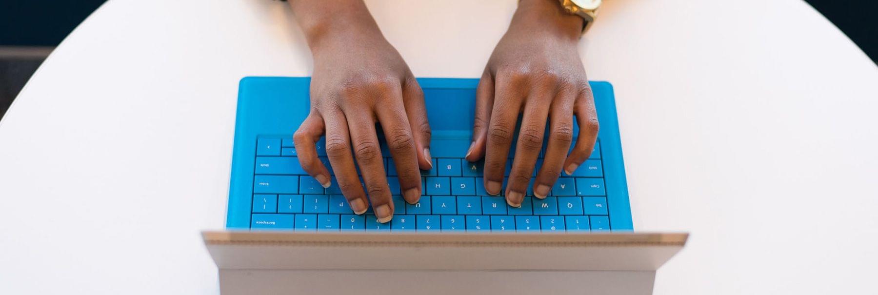 Hands typing on a laptop keyboard.